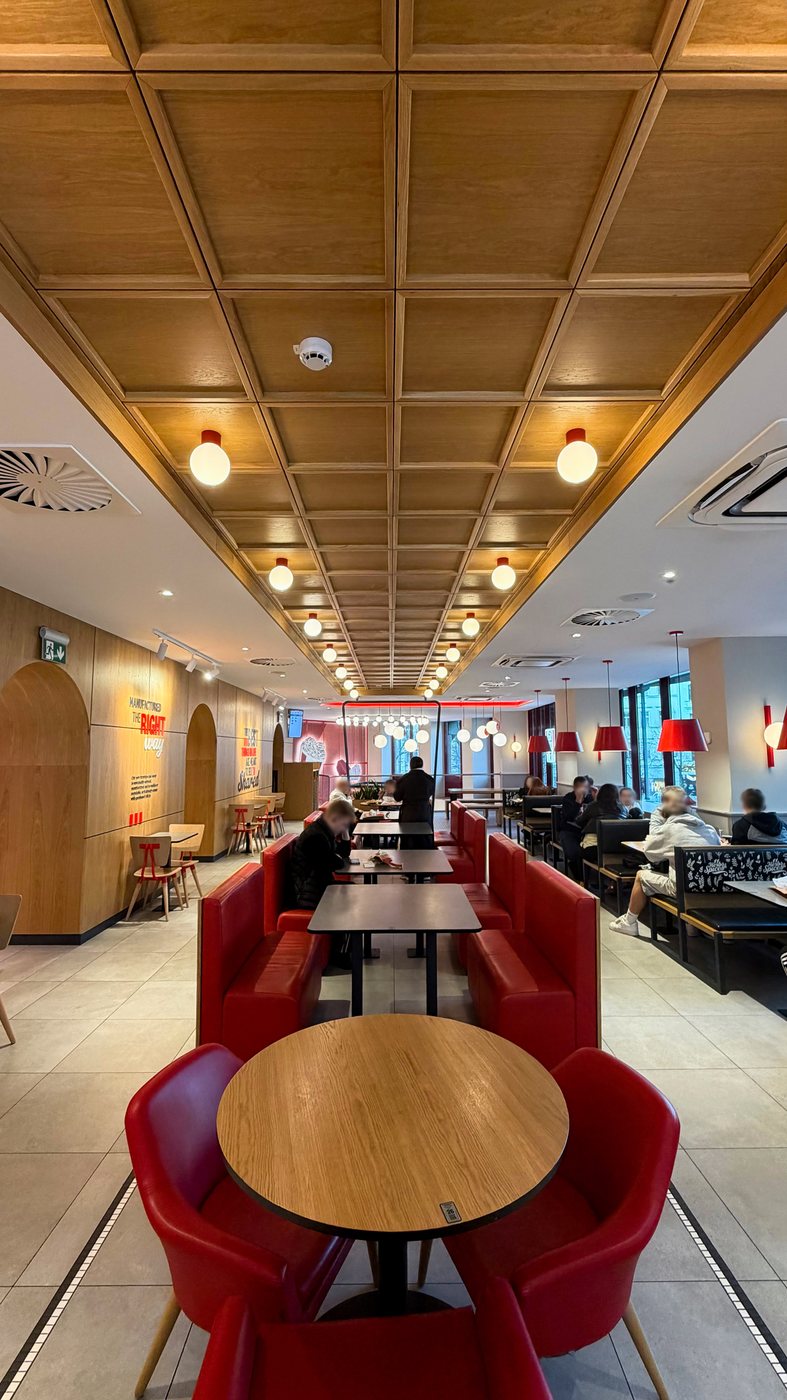 KFC VN40 — dining hall under a coffered oak ceiling with red leather booths